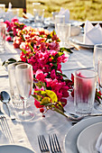 Gedeckter Tisch im Freien dekoriert mit Bougainvillea-Blütengirlande