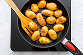 Unpeeled potatoes being fried in a pan