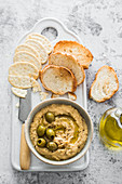 Hummus provenzal with olives and herbs, served with bread and crackers