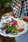 Frau serviert Blattsalat mit rosa Grapefruit