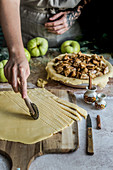 Preparing apple pie, cutting dough, apples with cinnamon in a baking form