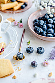 Blueberries in a bowl, in the background cookies with blueberry jam