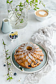 Easter cake with blueberries and lemon, sprinkled with powdered sugar, coffee on the background