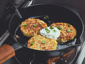 Corn fritters in a cast iron pan with sour cream and spring onions