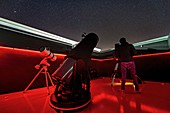 Telescopes and astronomer at an observatory at night