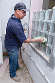 Man constructing glass brick window