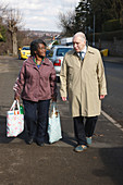 Carer carrying shopping for pensioner