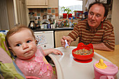 Grandfather feeding baby in kitchen