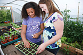 Woman with daughter planting seeds in a tray