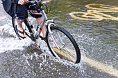 Cyclist rides bike through flooded street