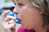 Middle aged woman with asthma using an inhaler