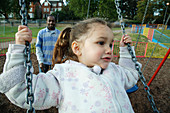 Man pushing girl on a swing