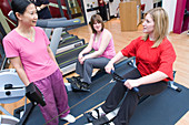 Fitness instructor showing women how to use a rowing machine