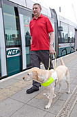 Vision impaired man with guide dog on tram platform