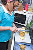 Teenaged girl slicing up a pineapple