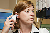 Woman at work taking temperature with digital thermometer