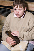 Young woman with learning disabilities stroking a guinea pig