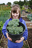 Woman with learning disability with broccoli on allotment