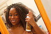 Young black woman putting on hair oil