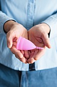 Close-up of hands holding a pink menstrual cup