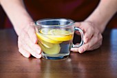 Close-up of hands holding lemon and ginger tea