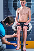 Physical therapist measuring teenage boy's shin