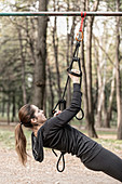 Woman exercising with hanging fitness straps