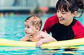 Baby with instructor in swimming pool