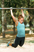Woman exercising on horizontal bar outdoors