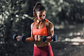 Woman exercising with dumbbells outdoors