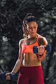 Woman exercising with dumbbells outdoors