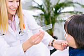 Paediatrician examining boy's eyes with ruler