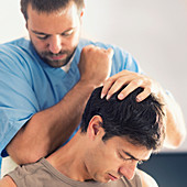 Physiotherapist massaging man's shoulders