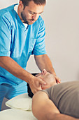 Physiotherapist massaging man's neck