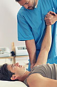 Physiotherapist stretching man's arm