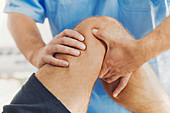 Physiotherapist massaging man's knee