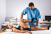 Physical therapist stretching woman's leg