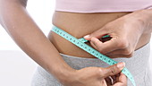 Woman measuring tummy with tape measure