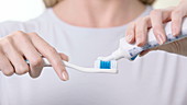 Woman applying toothpaste to brush