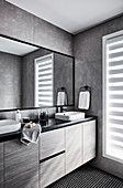 Elegantes Badezimmer mit Waschtischmöbel und grauen Wandlfiesen