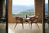 Wicker armchairs and delicate table on Mediterranean terrace with view of landscape