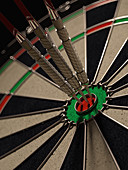 Three darts hitting bull's eye on dartboard, illustration