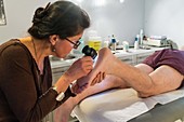 Dermatologist examining the skin of a patient