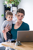 Woman using laptop computer with toddler