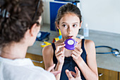 Doctor instructing a girl on how to use asthma inhaler