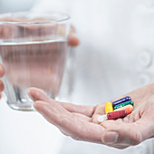 Hands with colourful pills and a glass of water