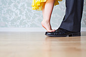 Young girl standing on father's feet