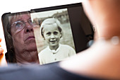 Senior woman looking at her younger self on a tablet compute