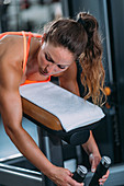 Female athlete using lying leg curl bench in the gym