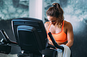 Woman exercising on cycling machine